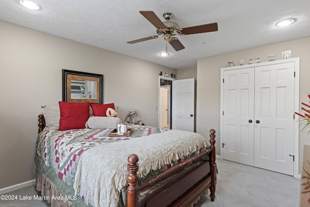 carpeted bedroom with ceiling fan, a closet, and a textured ceiling