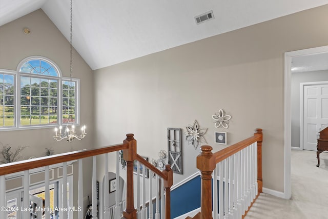 hall with carpet flooring, high vaulted ceiling, and a notable chandelier