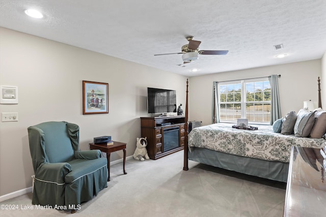 bedroom featuring a textured ceiling, ceiling fan, and light carpet