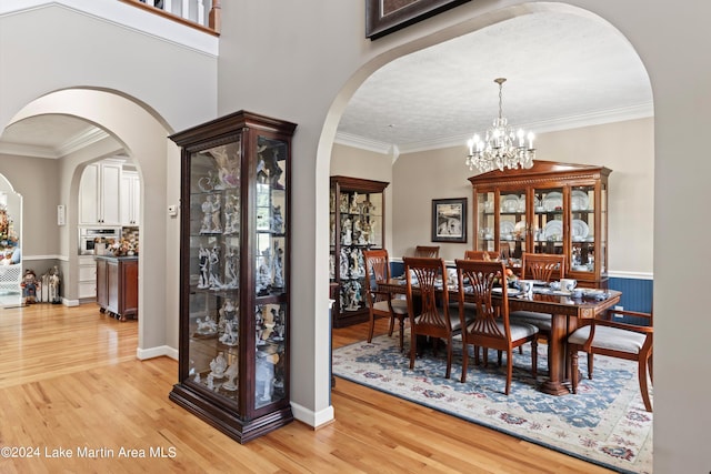 dining area with a notable chandelier, light hardwood / wood-style floors, and ornamental molding