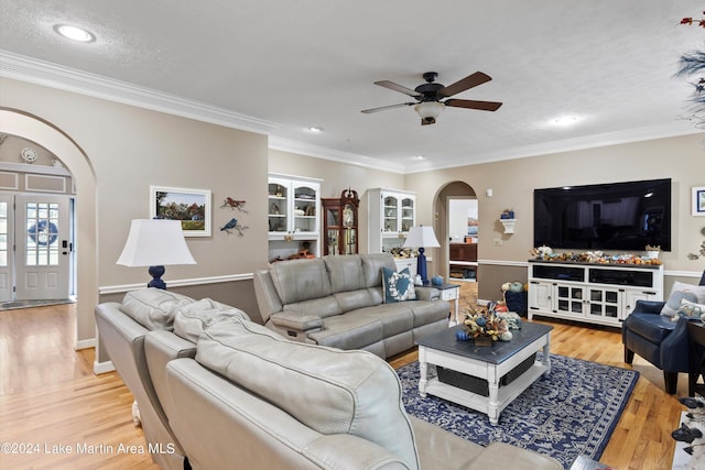 living room featuring a textured ceiling, light wood-type flooring, ceiling fan, and crown molding