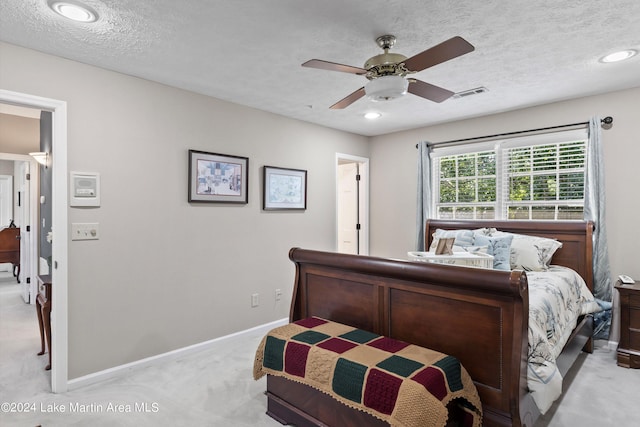 bedroom featuring ceiling fan, light colored carpet, and a textured ceiling