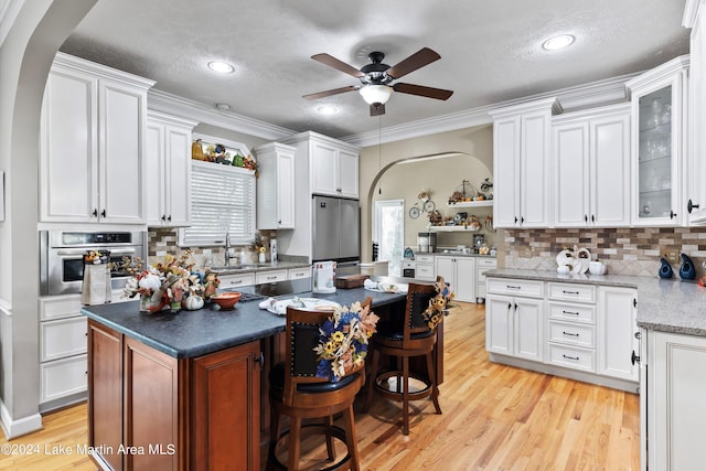 kitchen with white cabinets, a kitchen island, crown molding, and appliances with stainless steel finishes