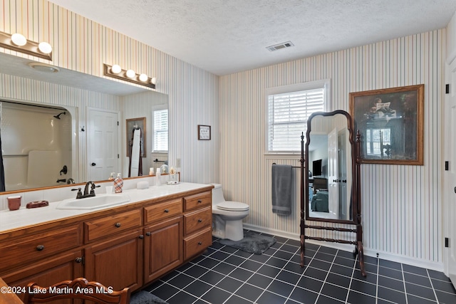 bathroom featuring tile patterned floors, a shower, a textured ceiling, toilet, and vanity