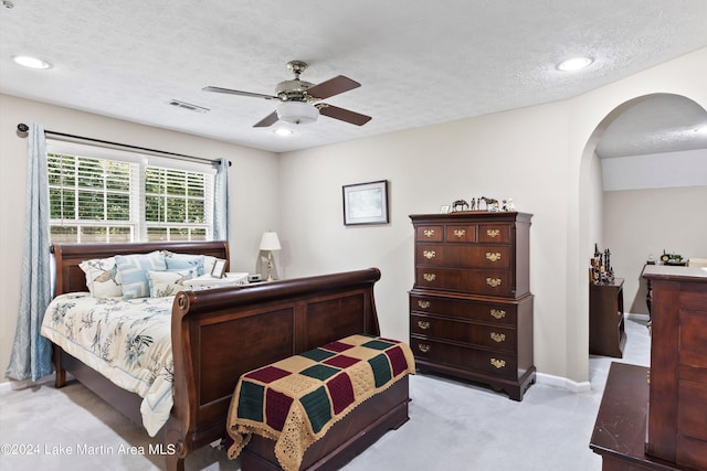 carpeted bedroom featuring ceiling fan and a textured ceiling