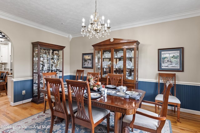 dining area with crown molding, a chandelier, a textured ceiling, and light wood-type flooring