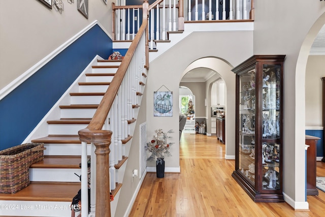 staircase featuring hardwood / wood-style floors, a high ceiling, and ornamental molding