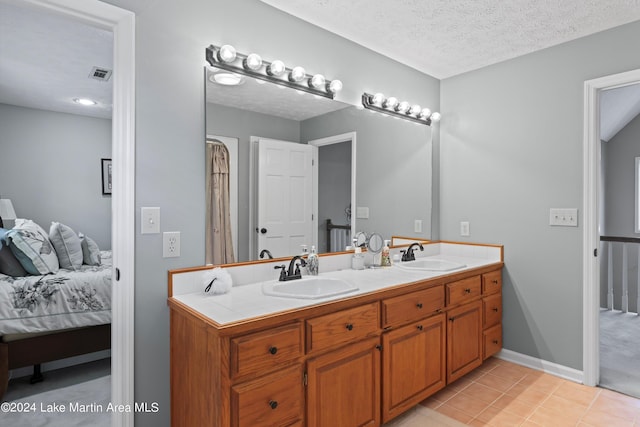 bathroom with tile patterned flooring, vanity, and a textured ceiling