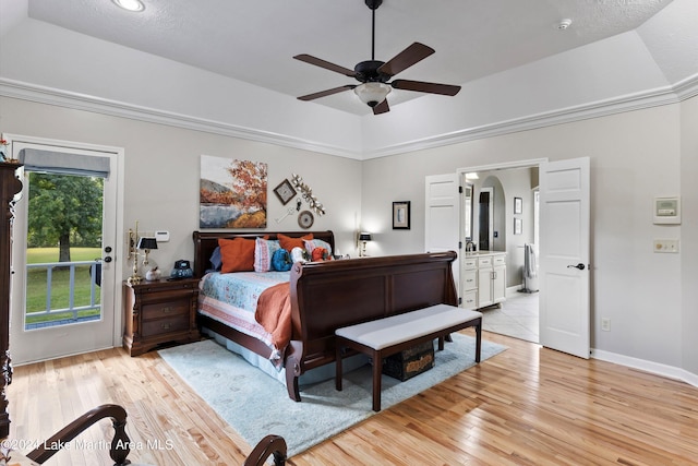 bedroom featuring ceiling fan, access to exterior, light wood-type flooring, and a tray ceiling