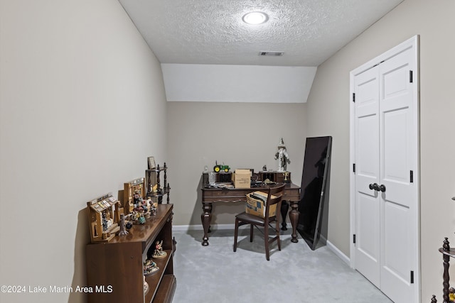 office area with a textured ceiling, light colored carpet, and vaulted ceiling