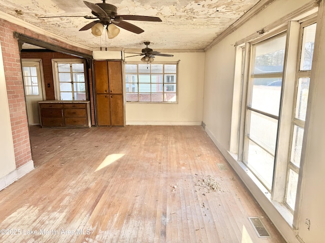 unfurnished room featuring a healthy amount of sunlight, light wood-style floors, visible vents, and ornamental molding