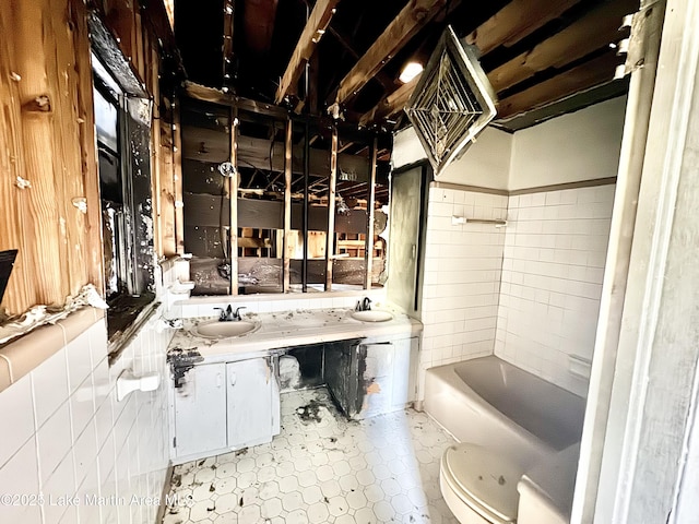 bathroom featuring a tub, a sink, toilet, and double vanity