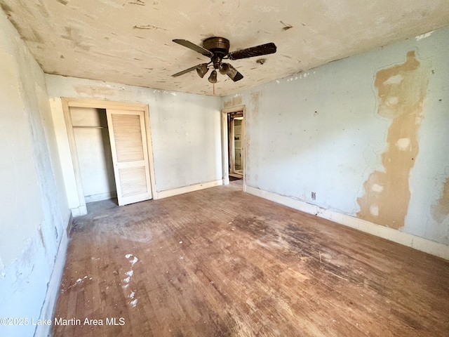 unfurnished bedroom with ceiling fan, a closet, and wood finished floors