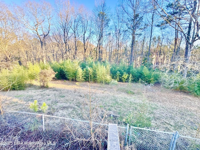 view of yard with a wooded view and fence