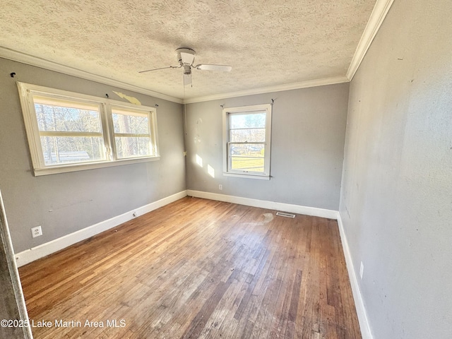 spare room with baseboards, a textured ceiling, ornamental molding, and hardwood / wood-style floors