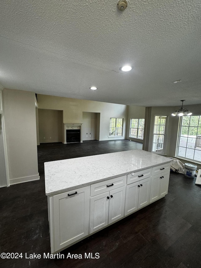 kitchen with dark hardwood / wood-style floors, white cabinetry, a healthy amount of sunlight, and a textured ceiling