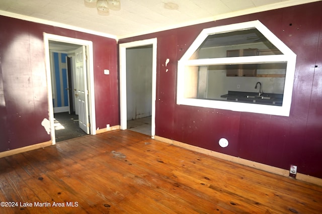 spare room with hardwood / wood-style flooring, sink, and crown molding