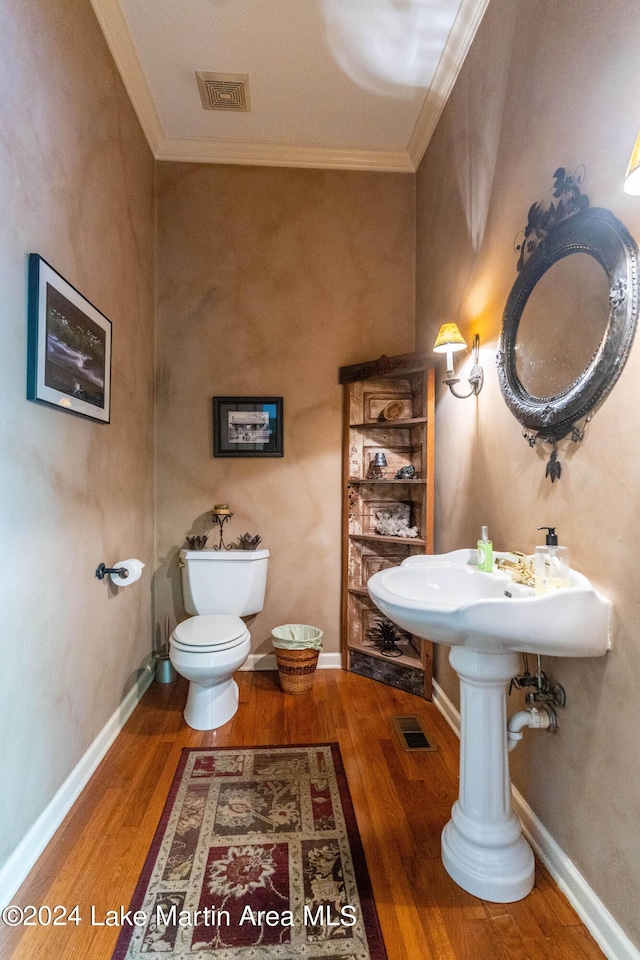 bathroom with hardwood / wood-style flooring, toilet, and crown molding