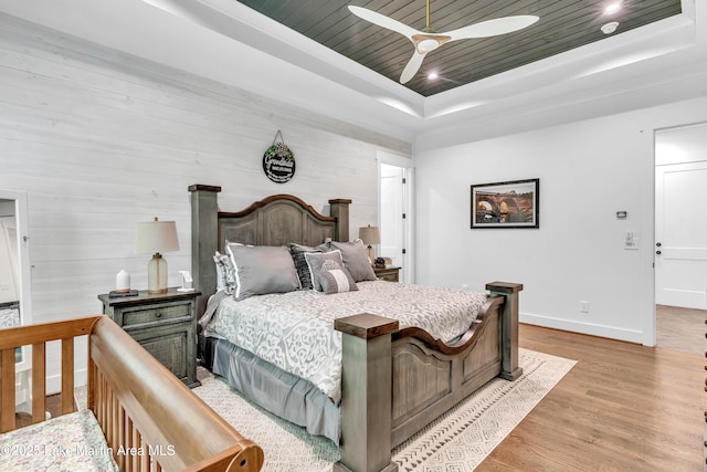 116 Glynmere Park, Alexander City, AL 35010 - bedroom featuring a tray ceiling, light wood-type flooring, baseboards, a ceiling fan, and wooden walls