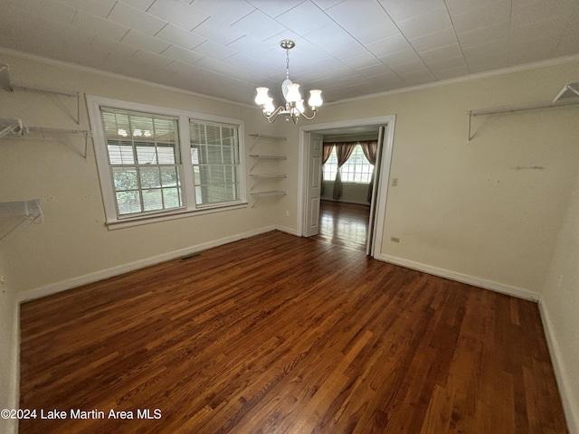 unfurnished dining area with a notable chandelier, dark hardwood / wood-style flooring, and crown molding