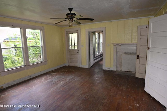 unfurnished living room featuring ornamental molding, ceiling fan, and dark wood-type flooring