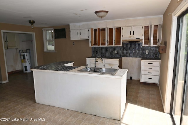 kitchen with backsplash, electric water heater, sink, and white cabinets