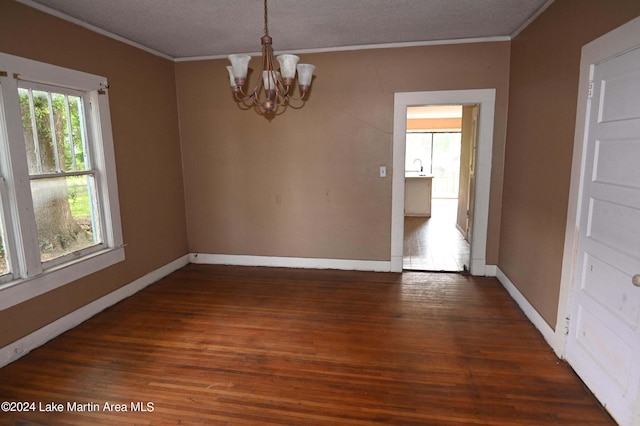 unfurnished dining area featuring a notable chandelier, dark hardwood / wood-style flooring, a textured ceiling, and crown molding