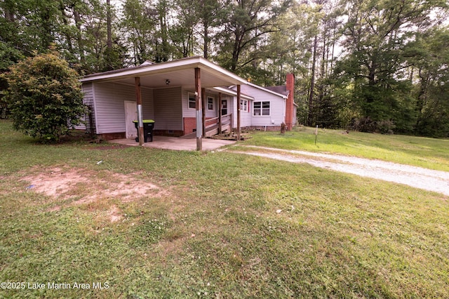 view of front facade with a chimney, an attached carport, driveway, crawl space, and a front lawn