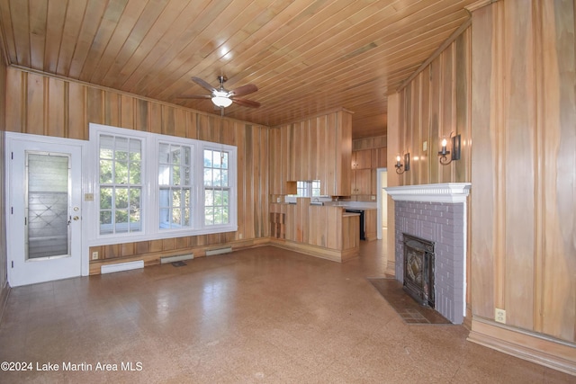 unfurnished living room with a fireplace, ceiling fan, wooden ceiling, and wood walls