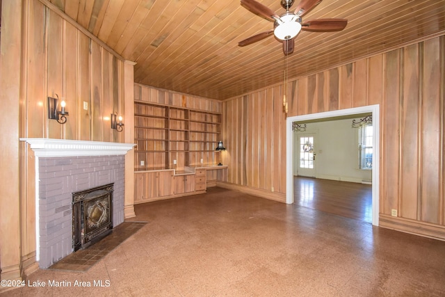 unfurnished living room featuring built in features, wooden ceiling, a fireplace, and wooden walls