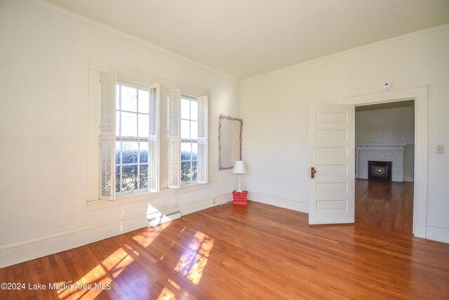 spare room featuring hardwood / wood-style flooring, ornamental molding, and a baseboard heating unit