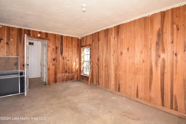 empty room featuring wood walls and concrete flooring