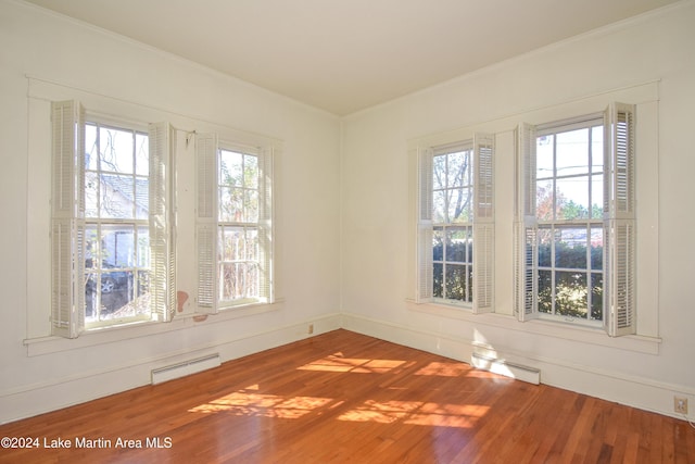 spare room with hardwood / wood-style flooring, ornamental molding, and a baseboard radiator