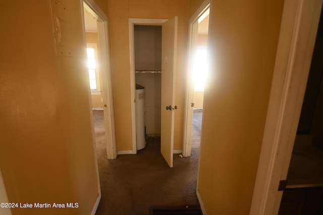 hallway with water heater and dark colored carpet