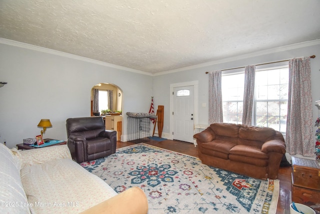 living area with arched walkways, a textured ceiling, wood finished floors, and crown molding