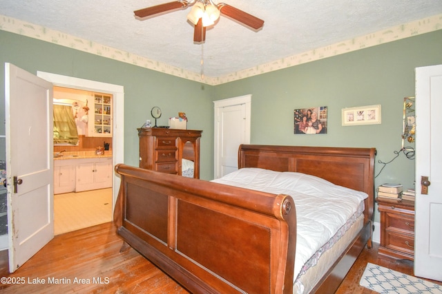 bedroom with ceiling fan, a textured ceiling, wood finished floors, and ensuite bathroom