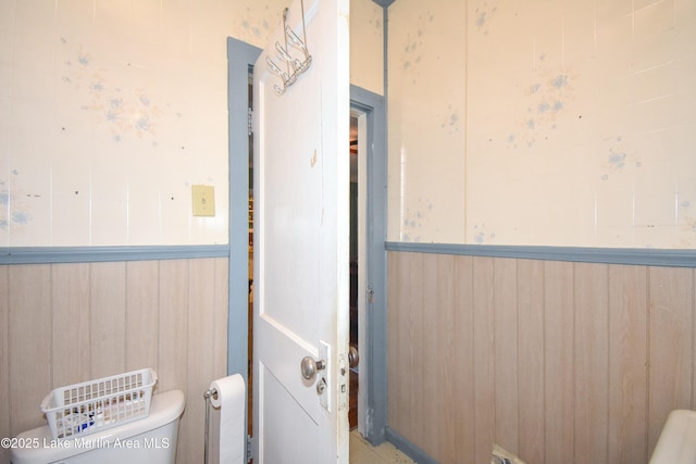 bathroom with wooden walls, wainscoting, and toilet
