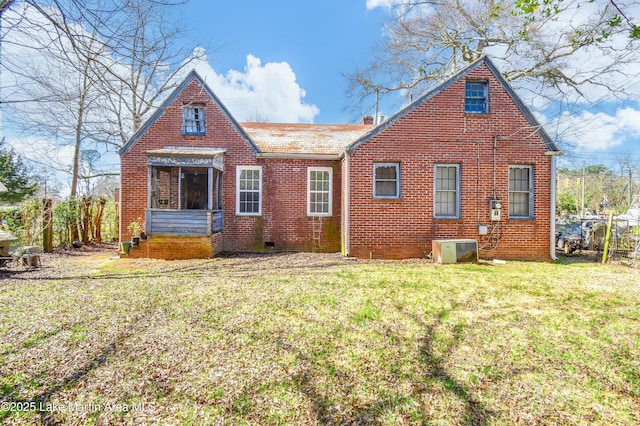 rear view of property with a yard, brick siding, and central AC