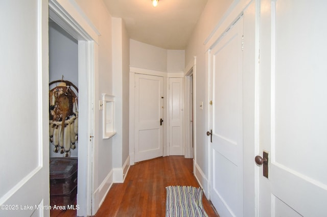 hallway featuring baseboards and dark wood-style flooring