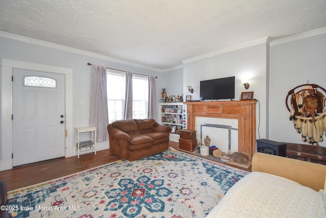 living room featuring a textured ceiling, wood finished floors, a fireplace, and ornamental molding