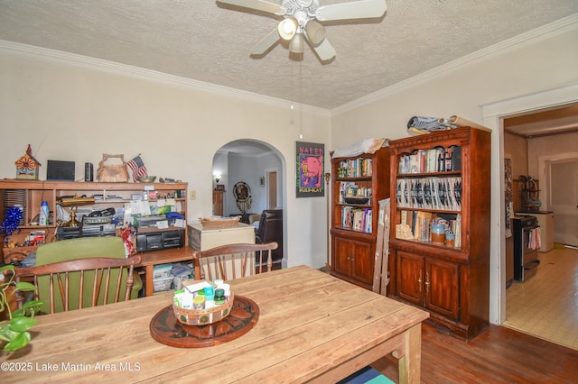dining area featuring crown molding, wood finished floors, arched walkways, a textured ceiling, and a ceiling fan