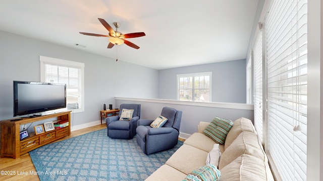 living area with wood finished floors, baseboards, ceiling fan, and visible vents