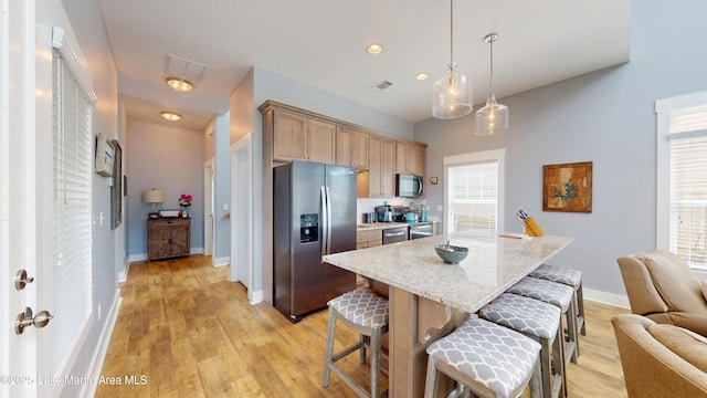 kitchen featuring light wood-style flooring, stainless steel appliances, a breakfast bar, and visible vents