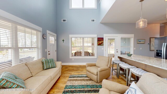 living room with light wood-style flooring, plenty of natural light, and visible vents