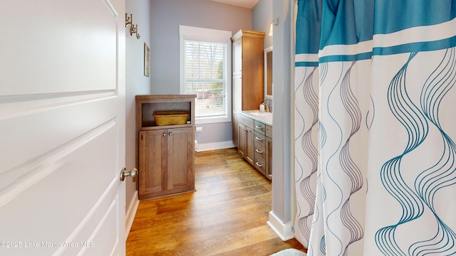 bathroom featuring vanity, curtained shower, baseboards, and wood finished floors