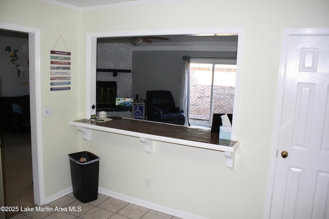 kitchen with ceiling fan, tile patterned flooring, a breakfast bar, baseboards, and ornamental molding