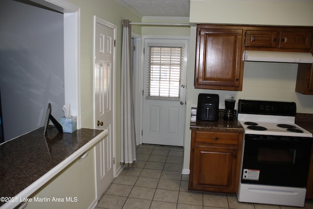 kitchen with light tile patterned floors, electric stove, range hood, dark countertops, and crown molding