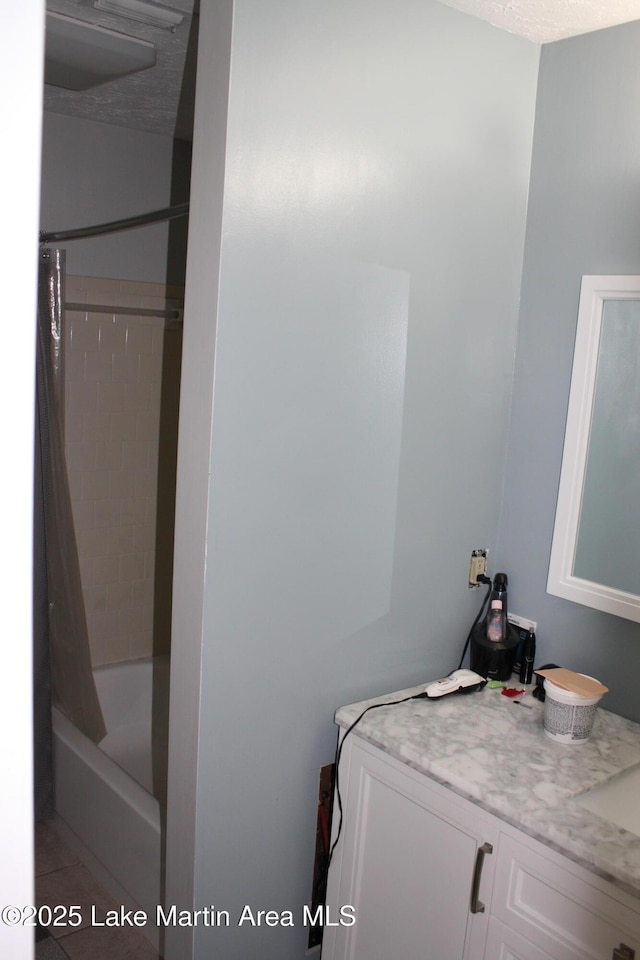 bathroom with shower / bath combo with shower curtain, a textured ceiling, and vanity