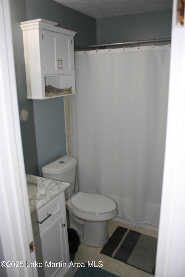 bathroom featuring a shower with curtain, toilet, vanity, and a textured ceiling