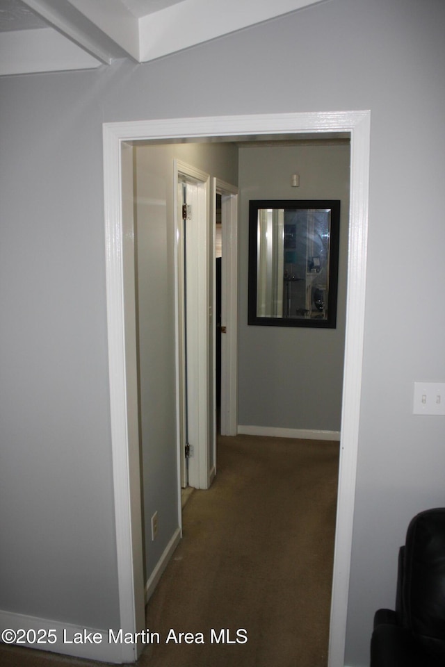 corridor featuring baseboards and carpet flooring